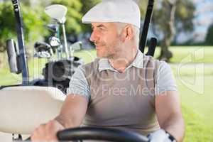 Happy golfer driving his golf buggy