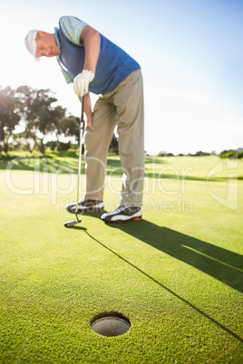 Golfer standing on the putting green watching hole