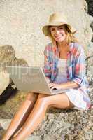 Pretty blonde using laptop at the beach