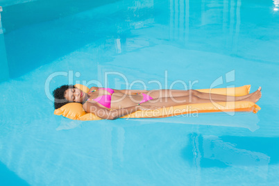 Fit woman lying on lilo in swimming pool