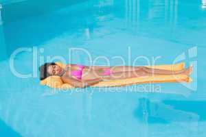Fit woman lying on lilo in swimming pool