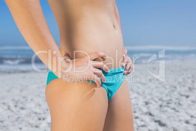 Mid section of fit woman in bikini on the beach