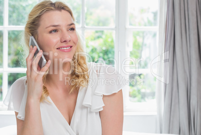 Pretty blonde sitting on bed on the phone