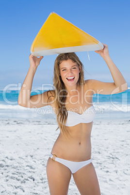 Smiling surfer girl holding her surfboard on the beach