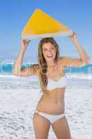 Smiling surfer girl holding her surfboard on the beach