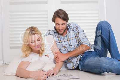 Happy couple sitting on floor doing crossword