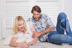 Happy couple sitting on floor doing crossword