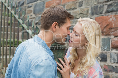 Hip young couple standing by railings about to kiss
