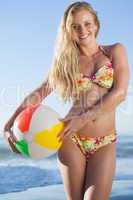 Gorgeous blonde in floral bikini holding beach ball