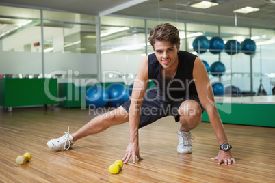 Fit smiling man warming up in fitness studio
