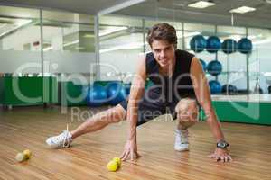 Fit smiling man warming up in fitness studio