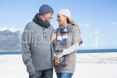 Smiling couple standing on the beach in warm clothing