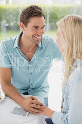 Hip young couple smiling at each other at table