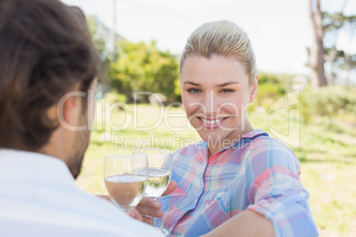 Happy young couple sitting in the garden enjoying wine together