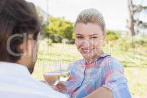 Happy young couple sitting in the garden enjoying wine together