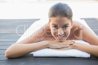 Happy brunette lying on a towel poolside