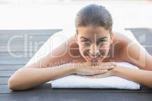 Happy brunette lying on a towel poolside