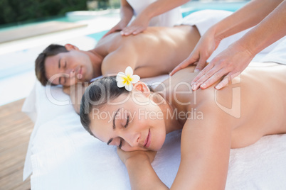 Attractive couple enjoying couples massage poolside