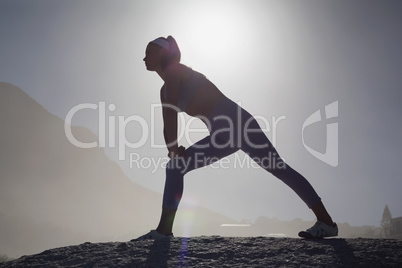 Sporty blonde stretching on the beach on a rock