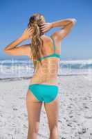 Fit woman in bikini on beach rear view