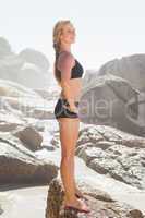 Fit blonde standing on the beach on a rock