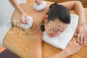 Smiling brunette getting a herbal compress massage