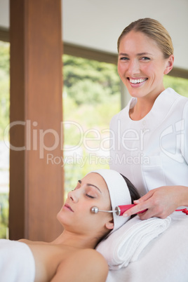 Brunette getting micro dermabrasion with therapist smiling at ca