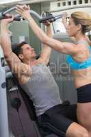 Personal trainer coaching bodybuilder using weight machine