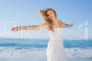 Beautiful blonde in white sundress on the beach smiling