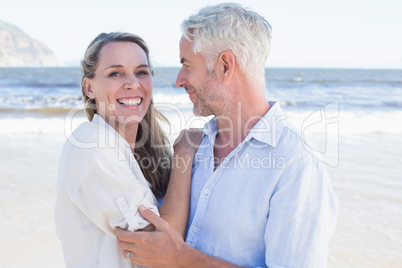 Happy couple hugging on the beach woman looking at camera