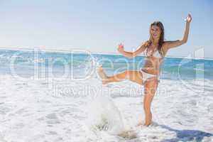 Beautiful smiling woman in white bikini splashing on the beach