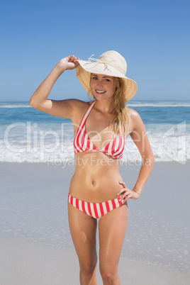 Gorgeous fit woman in striped bikini and sunhat at beach