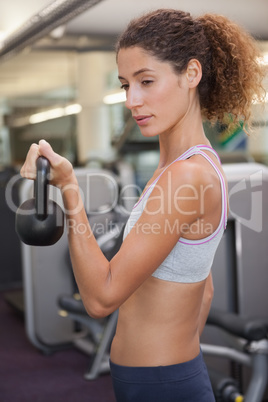 Fit woman lifting up kettlebell