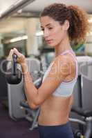 Fit woman lifting up kettlebell