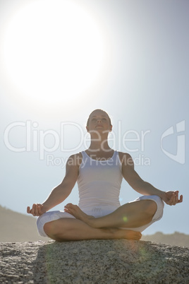 Blonde woman sitting in lotus pose on beach