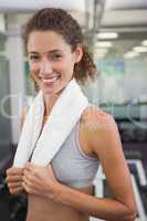 Fit woman smiling at camera with towel around shoulders