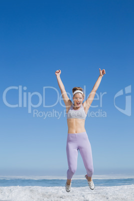 Sporty happy blonde jumping on the beach