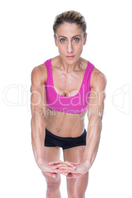 Female bodybuilder flexing with hands together looking at camera