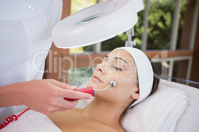 Peaceful brunette getting micro dermabrasion from beauty therapi