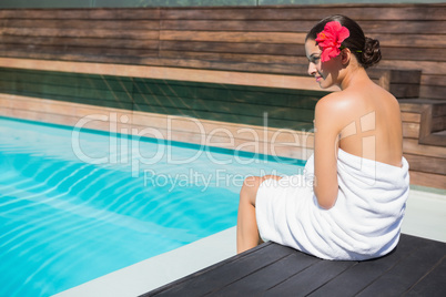 Beautiful brunette in towel sitting by the pool