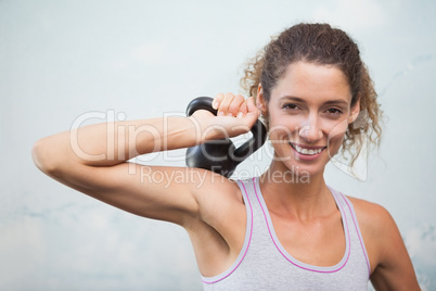 Fit woman smiling at camera holding kettlebell