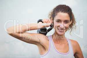 Fit woman smiling at camera holding kettlebell