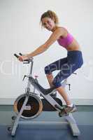 Fit woman on the spin bike smiling at camera