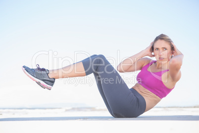 Fit blonde sitting in boat position on the beach