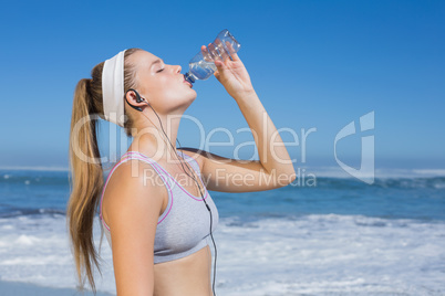 Sporty blonde on the beach drinking water