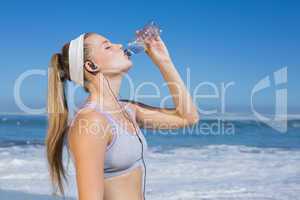 Sporty blonde on the beach drinking water