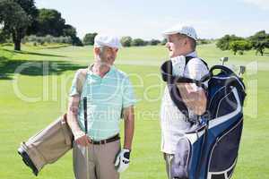 Golfer friends chatting and holding their golf bags