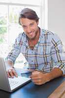 Smiling casual man using laptop to shop online