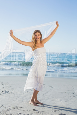 Beautiful happy blonde in white sundress on the beach with scarf