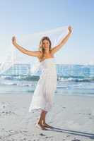 Beautiful happy blonde in white sundress on the beach with scarf